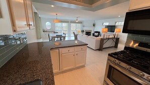A spacious kitchen with granite countertops, a built-in oven, and a dining area with a table and chairs. - Lakefront Getaway on Murray Lake - Swim, Fish, Float, & Relax (Lowell)