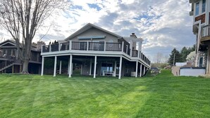A two-story house with a covered porch and a stone fireplace. - Lakefront Getaway on Murray Lake - Swim, Fish, Float, & Relax (Lowell)