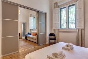 Een slaapkamer met een bed, een stoel, een kledingkast en een raam met gordijnen.
