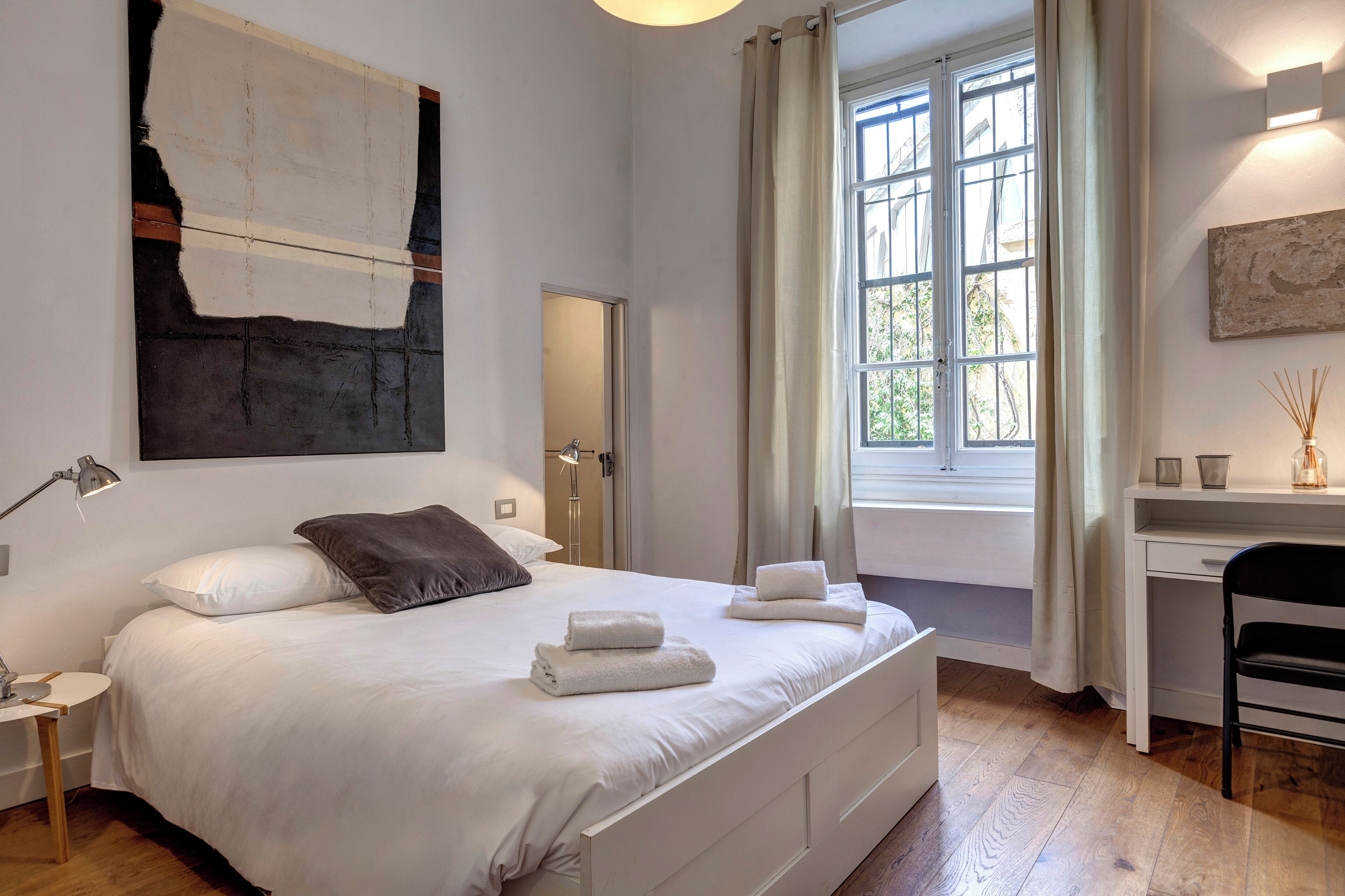 Une chambre moderne avec un grand lit, un bureau et une fenêtre avec des rideaux.