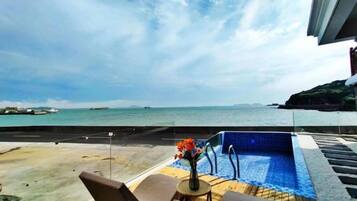 A pool area with a view of the sea and a beach.