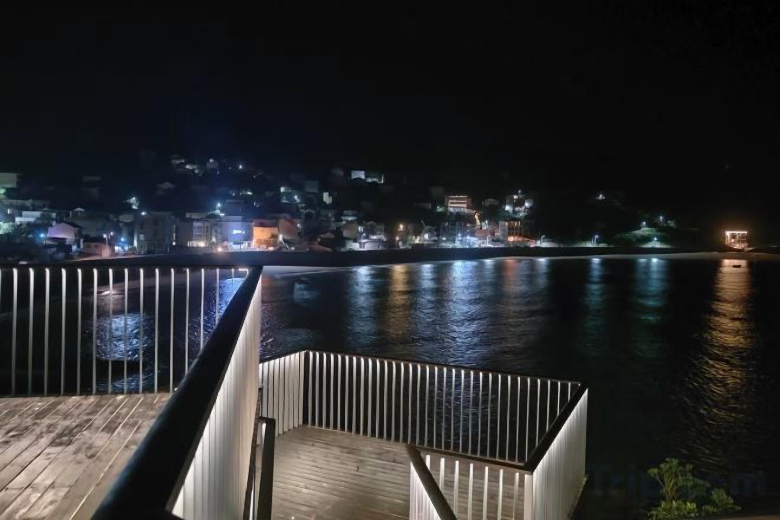 Vista al agua con muelle y barandilla de madera.