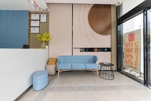 A reception area with a blue sofa, a small round table, and a vase with flowers.