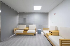 A modern, minimalist room with a sofa set, a small side table, and a blue trash bin. - Yuelin Hotel (Fuzhou)