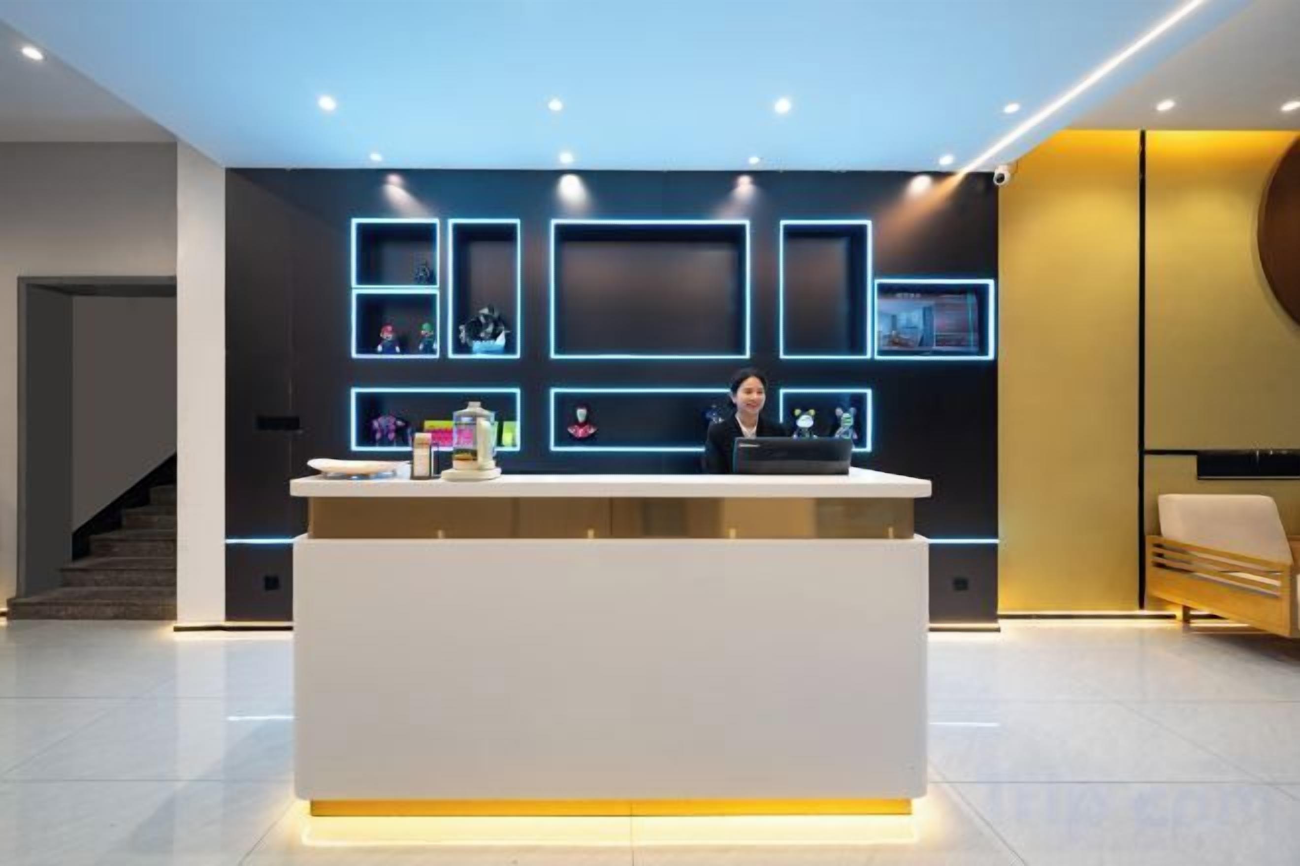 A reception desk with a modern design, a staircase in the background, and a seating area with a sofa.