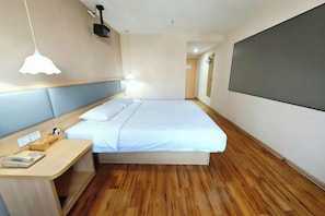 A hotel room with a bed, bedside table, and a large TV screen.
