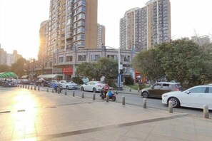 A city street with high-rise buildings, parked cars, and a clear sky. - Mulan Hotel (Shanghai)