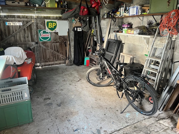 A garage with a bicycle, a red ATV, and various tools and equipment.
