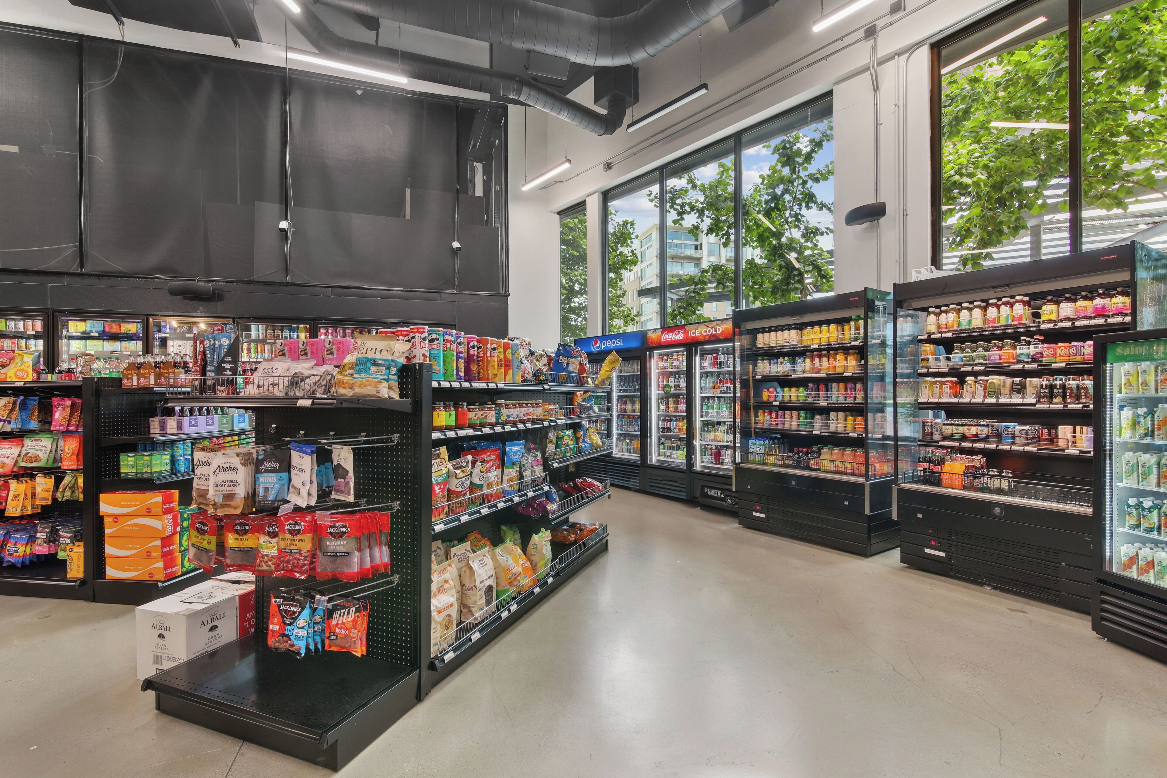 Een gangpad in een supermarkt, gevuld met schappen vol snacks, drankjes en verpakte producten.