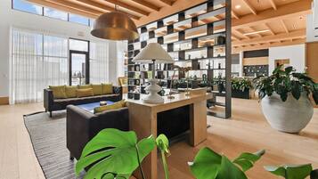 A modern interior with a sofa, a coffee table, a large potted plant, and a bookshelf.