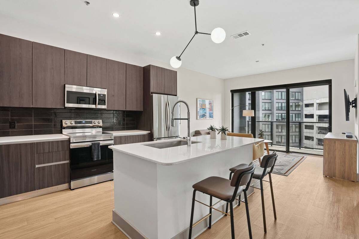 A modern kitchen with dark wood cabinets, stainless steel appliances, and a central island with bar stools.
