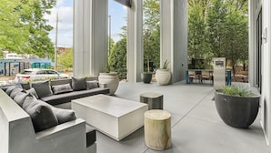 An outdoor seating area with a sofa, coffee table, and planters. - Sentral West Midtown At Star Metals (Atlanta)