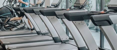 A gym with multiple treadmills and a person using one.