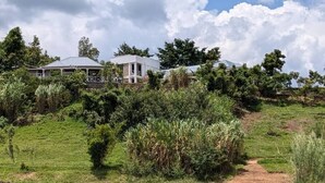 A lakeside property with a house surrounded by lush greenery and a clear view of the lake. - Ineza Guest House (Kinoni)