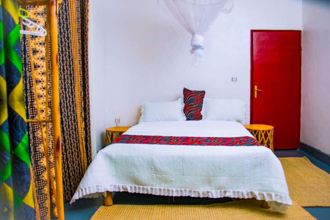 A room with a bed, a red door, and a white wall.
