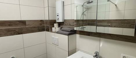 Un baño moderno con inodoro, lavabo y cabina de ducha de vidrio.