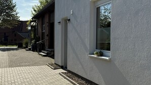 En moderne bygning med en belagt indkørsel, et lille vindue med en plante og en dør.