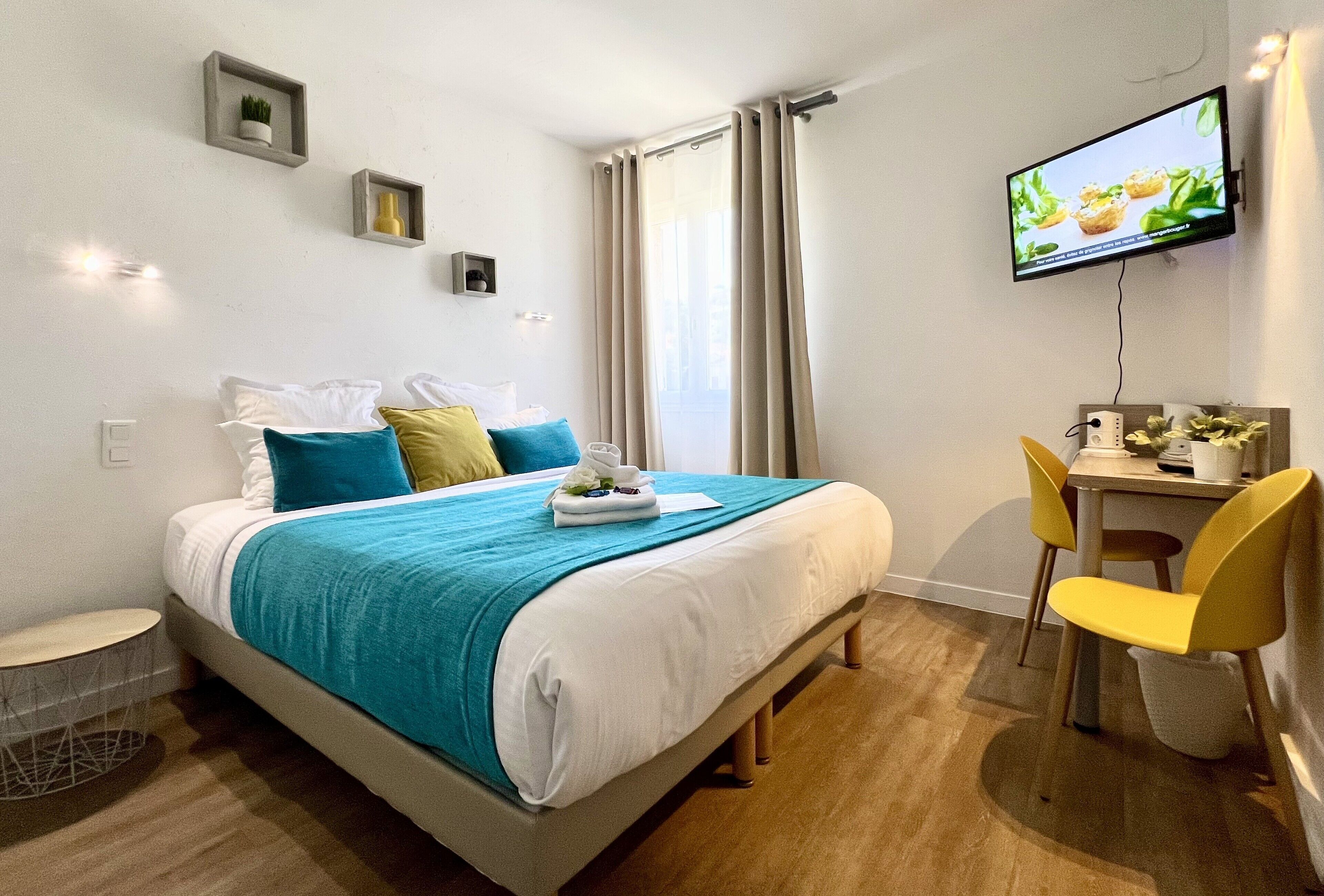 Une chambre d’hôtel moderne équipée d’un lit, d’un bureau et d’une télévision.