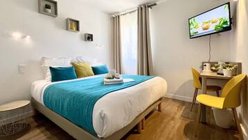 Une chambre d’hôtel moderne équipée d’un lit, d’un bureau et d’une télévision.