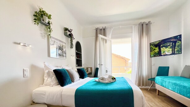 Un dormitorio moderno con cama, televisión, silla y vistas al balcón.