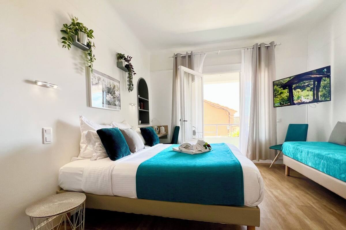 A modern bedroom with a bed, a TV, a chair, and a balcony view.