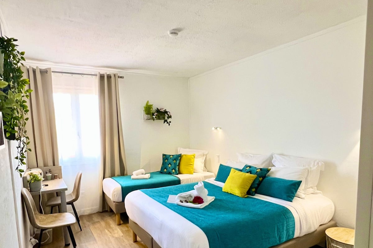 A hotel room with two beds, a desk, and a chair.