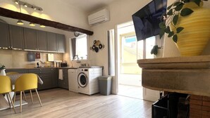 Una cocina moderna con armarios grises, lavadora y comedor con sillas amarillas.