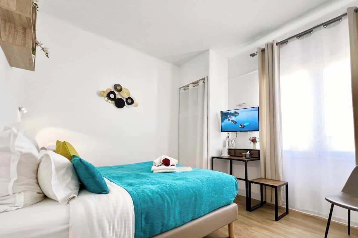 A modern hotel room with a bed, a desk, a TV, and a view of the outdoors.