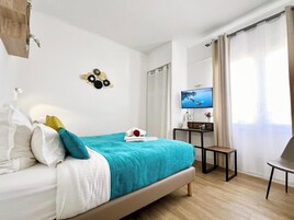 Una habitación de hotel moderna con cama, escritorio, televisor y vistas al exterior.