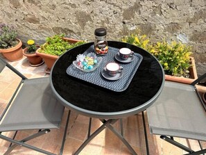 Ett runt bord med en svart, vadderad bordsskiva, två koppar med hjärtmotiv, en burk Nescafé Classic och en skål med färgglada godisbitar.