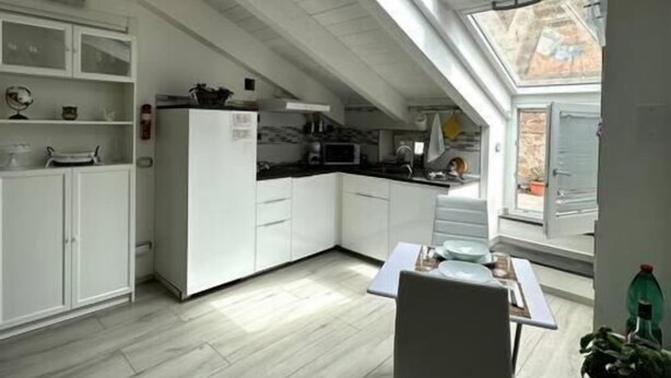 Una cocina moderna con armarios blancos, una mesa de comedor y un tragaluz.