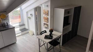 Una cocina moderna con comedor, muebles blancos y una pequeña mesa con sillas.