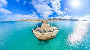 A pier extending into clear turquoise waters with a boat docked at the end. - SandyBeachApartment3 (Porto Santo)