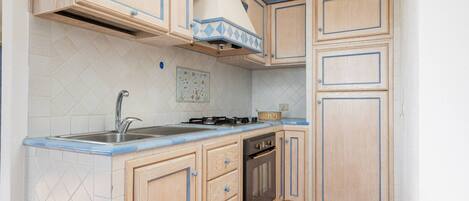 A kitchen with wooden cabinets, a sink, a stove, and a dishwasher.