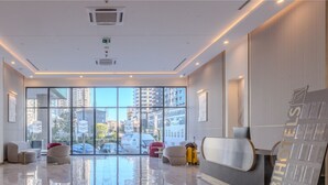 A modern hotel lobby with a large glass window, seating area, and a television screen. - ORBI CITY RightApart Hotel (Batumi)