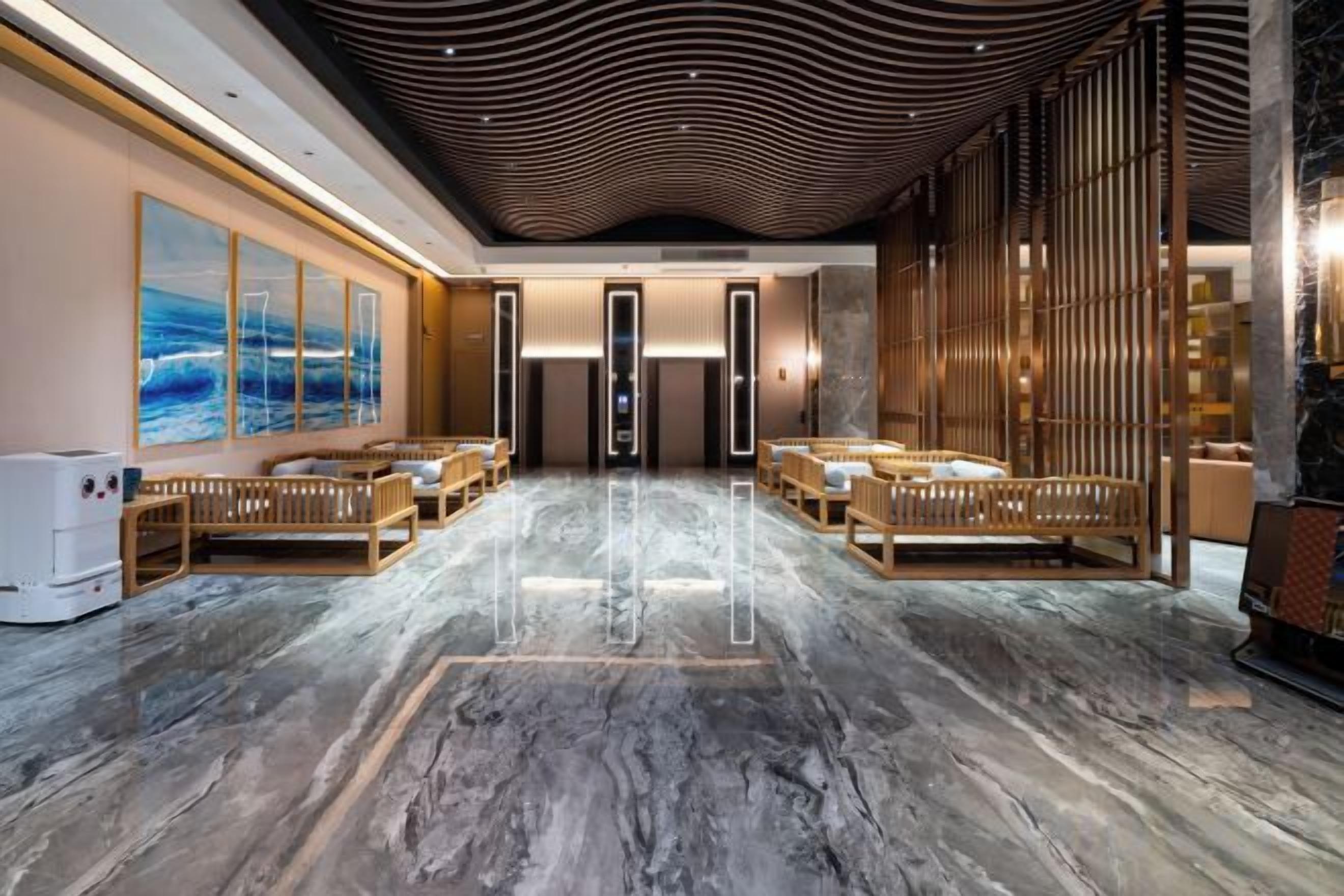 A spacious lobby with a marble floor, wooden seating, and a large abstract painting on the wall.