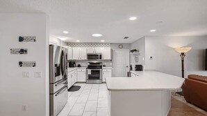 Una cocina moderna con armarios blancos, electrodomésticos de acero inoxidable y una isla central.