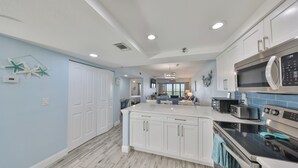A modern kitchen with white cabinets, a large island, and a built-in microwave.