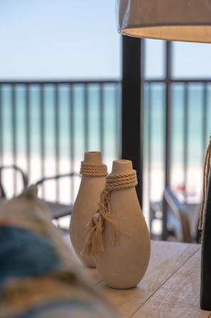Two ceramic vases with rope decorations on a wooden table, overlooking a balcony with a railing.