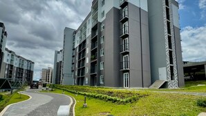 Un moderno edificio de apartamentos con varios pisos, una entrada en forma de curva y un césped bien cuidado.