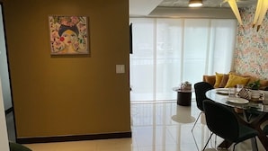 Una sala de estar moderna con comedor, ventanas amplias y techo con concreto a la vista.