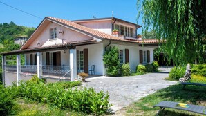 A two-story house with a tiled roof, a balcony, and a stone pathway leading to the entrance. - VILLA WITH POOL FOR 14 PEOPLE COMPLETELY FENCED IDEAL FOR VISITING (Marche)