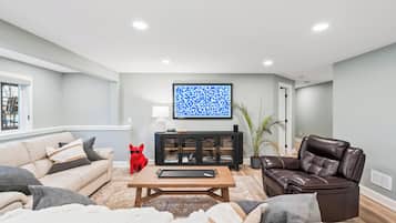 A modern living room with a beige sofa, a brown leather chair, a coffee table, and a black cabinet with glass doors.