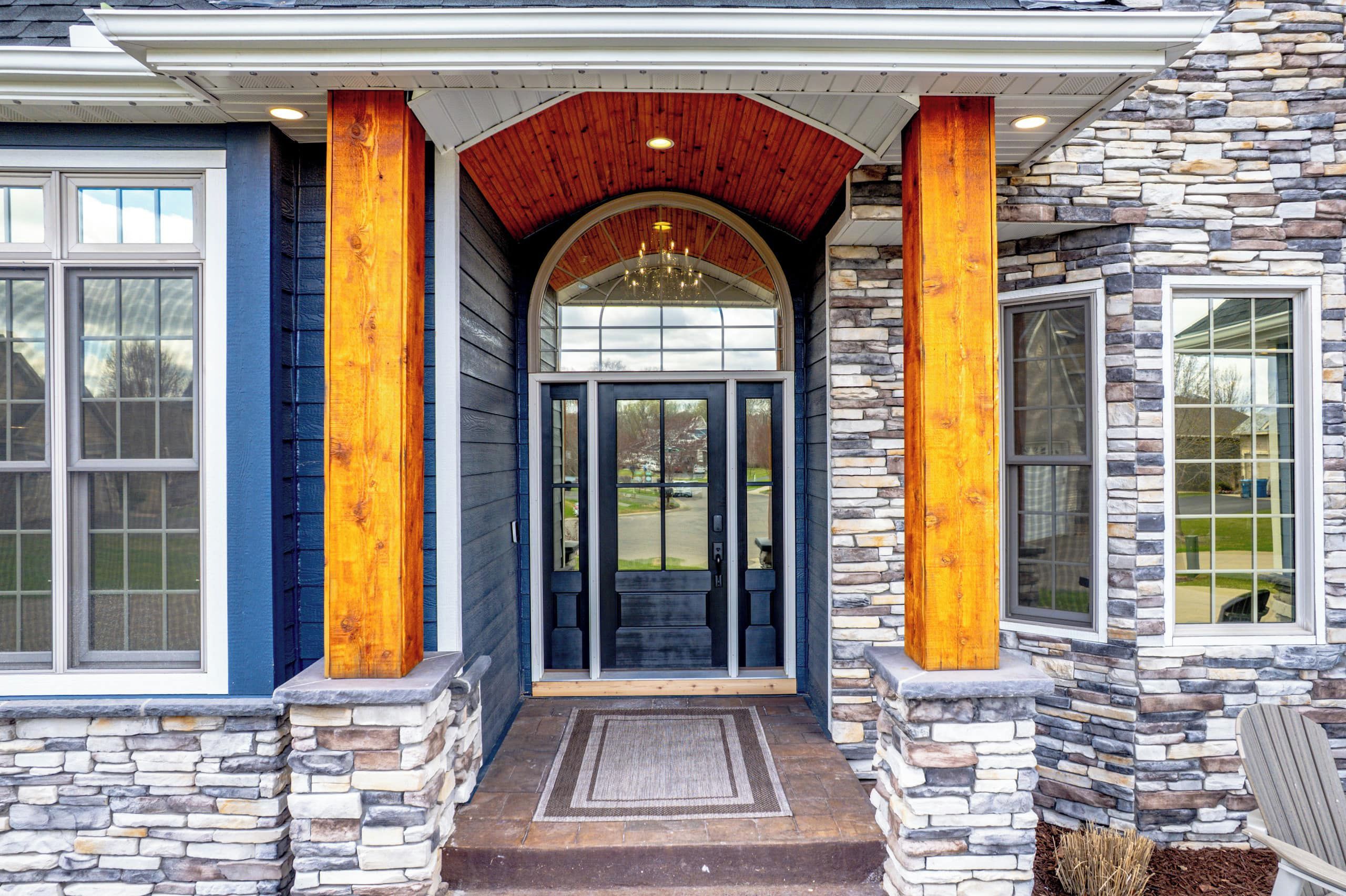 A house with a stone facade, a wooden porch, and a large arched entrance.