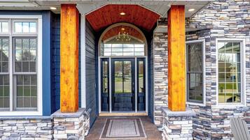 A house with a stone facade, a wooden porch, and a large arched entrance.