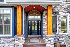 A house with a stone facade, a wooden porch, and a large arched entrance.