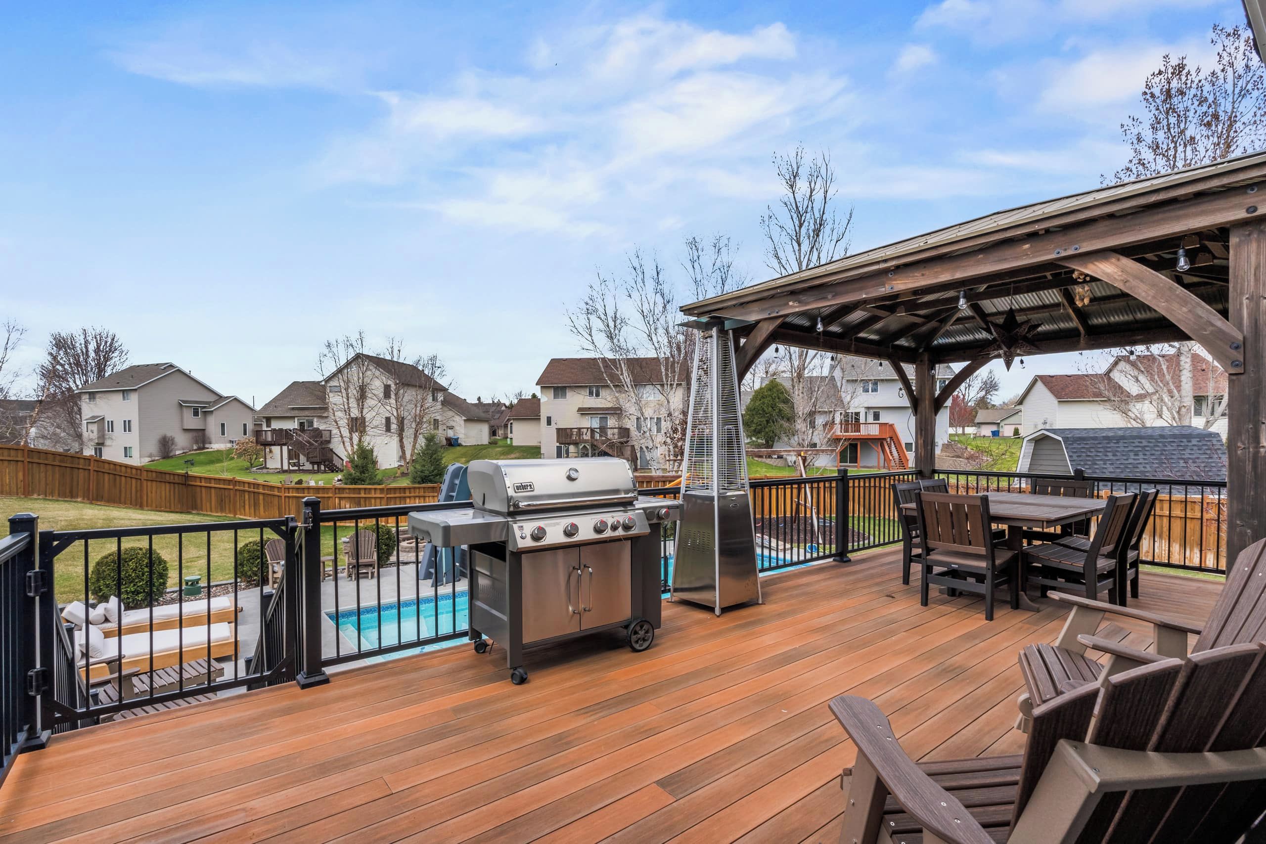 Une terrasse dotée d’un barbecue, d’un espace salon extérieur et offrant une vue sur un quartier résidentiel.