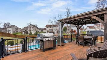 Une terrasse dotée d’un barbecue, d’un espace salon extérieur et offrant une vue sur un quartier résidentiel.