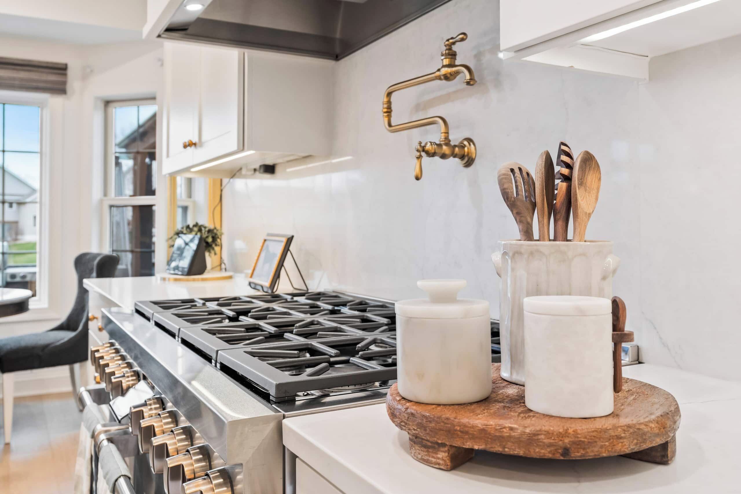 Una cocina moderna con estufa a gas, extractor, grifo y tabla de cortar de madera con utensilios.