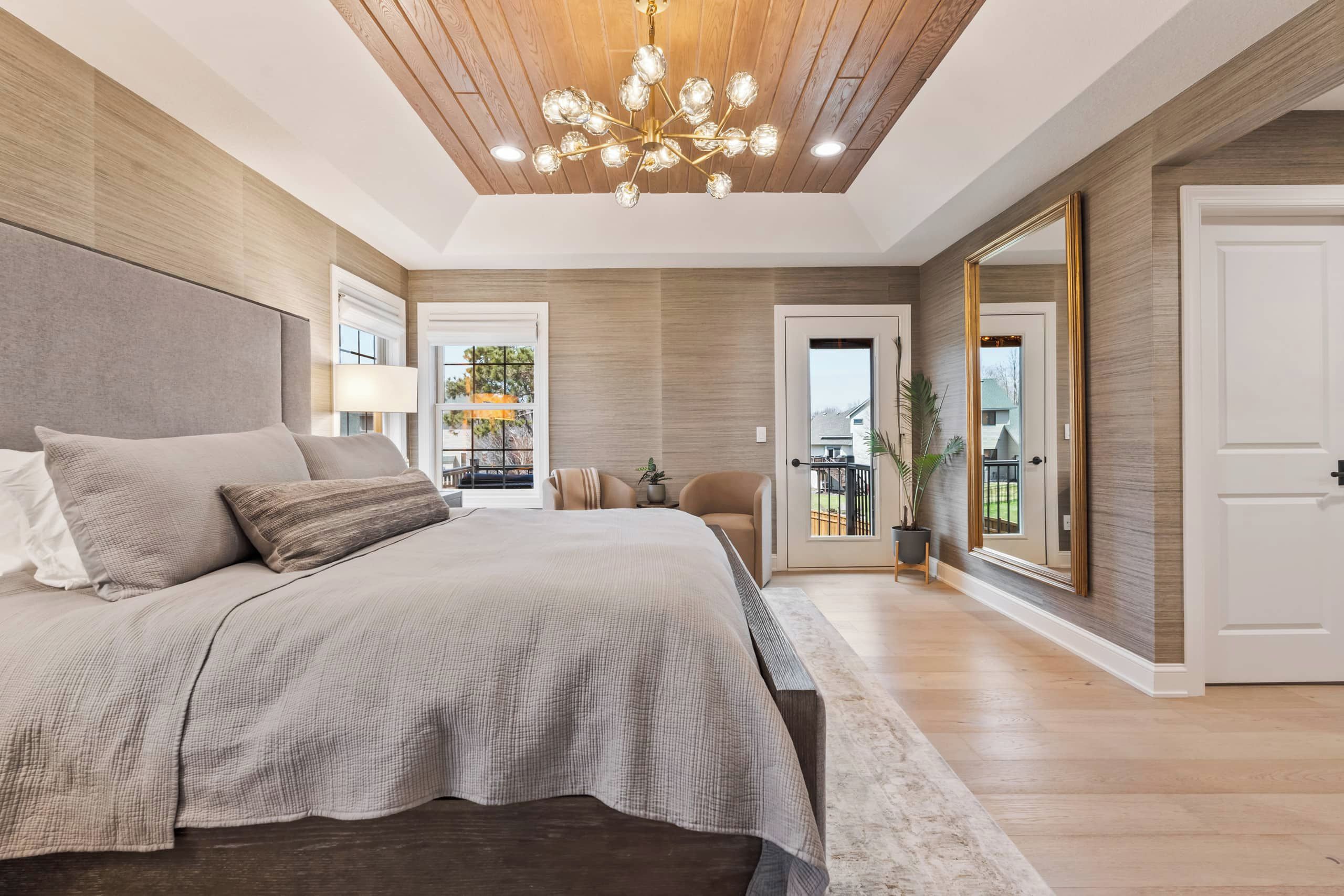 Un dormitorio moderno con una cama grande, una araña y vistas al exterior a través de una puerta.